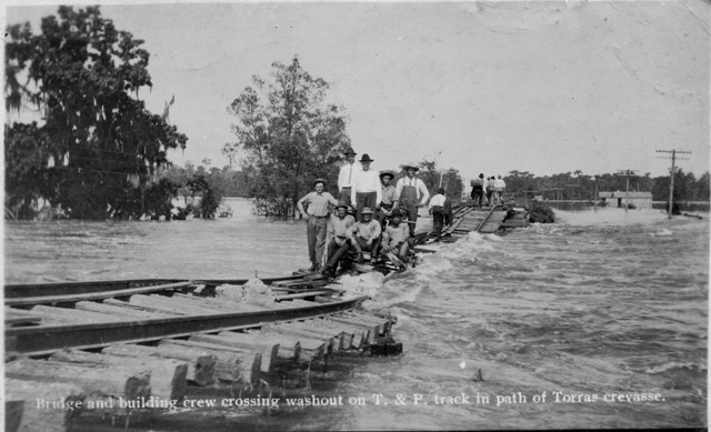 Bridge and building crew crossing washout on the Texas & Pacific (T&P) Railway track in path of Torras crevasse in Louisiana in 1912
